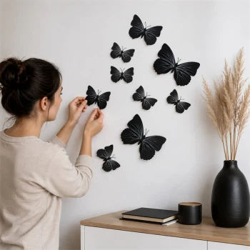 Person sætter 3D sorte sommerfugle wallstickers op på væg som moderne vægdekoration