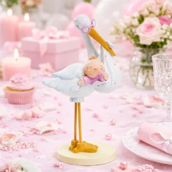 Barnedåbspynt stork med baby pige på bord dækket i lyserøde farver til baby shower og barnedåb