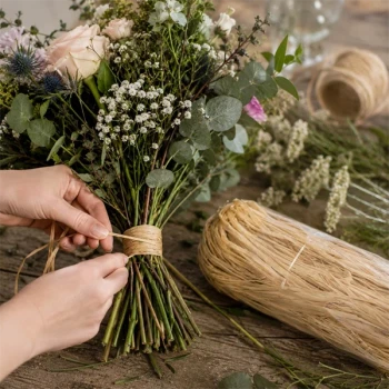 Person binder blomsterbuket med naturlig bastsnor i naturfarve. Bastsnor til buketbinding, blomsterdekorationer og kreative hobbyprojekter.