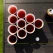 Beer pong bordopstilling med røde plastikkopper fyldt med drikkevarer og en hvid bold på bord