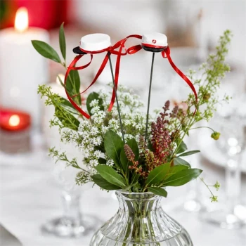 Blomsterpinde med røde studenterhuer placeret i blomsterdekoration på festbord til studentergilde og studenterfest.