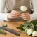 Person anvender blomsterpinde i metal 0,80 mm til blomsterbinding af en hvid rose på arbejdsbord med blomster og grønt.
