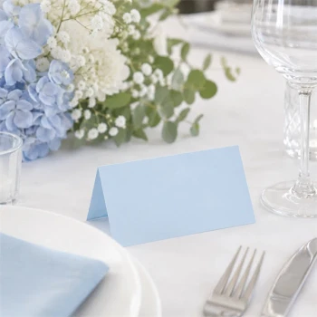 Lyseblåt tekstureret bordkort 10x7 cm placeret på elegant festbord med blomsterdekoration til bryllup, barnedåb og konfirmation