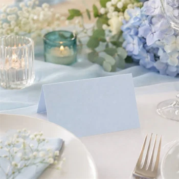 Lyseblåt tekstureret bordkort på elegant festbord med blomster, lys og borddækning til bryllup, barnedåb og babyshower