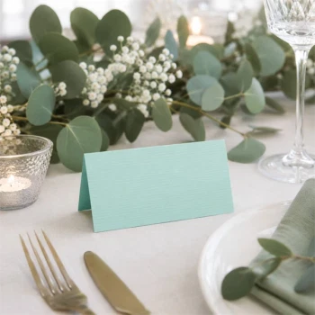 Mintgrønt tekstureret bordkort på elegant borddækning til bryllup med eucalyptus og stearinlys