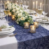 Pyntet festbord med mørk blå Sizoweb bordløber, blomsterdekoration og levende lys til bryllup og fest