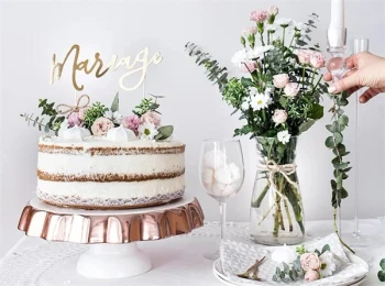 Bryllupskage med cake topper “Mariage” i guld pyntet med blomster på kagebord