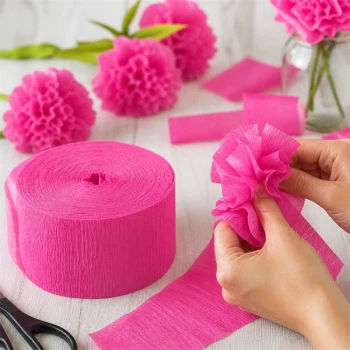 Person laver blomster af crepepapir hot pink – DIY pynt