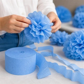 Person der laver papirblomst af lyseblå crepepapir – nem DIY pynt til fest og dekoration