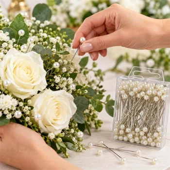 Hvide dekorationsnåle med perler brugt i blomsterdekoration med roser og grønt