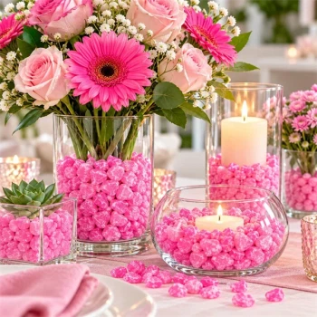Pink dekorationssten 5–8 mm i glasvaser med lyserøde roser, gerbera og levende lys som festlig bordpynt.