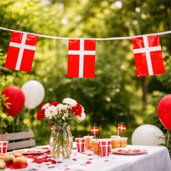 Flagguirlande med Dannebrog flag hængt over festbord i have med balloner og dansk pynt til fødselsdag