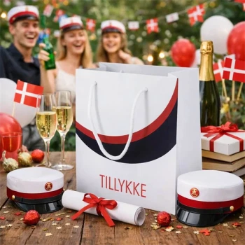 Rød student gavepose med teksten Tillykke placeret på bord til studenterfest med studenterhuer, champagne og danske flag