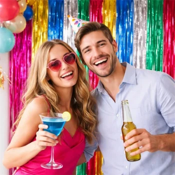 Par til fest foran multi glimmerforhæng som farverig photo booth baggrund med folie dørgardin