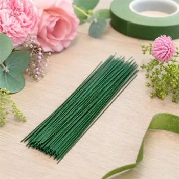 Grønne blomsterpinde i metal til blomsterbinding og papirblomster omgivet af blomster og floristmaterialer