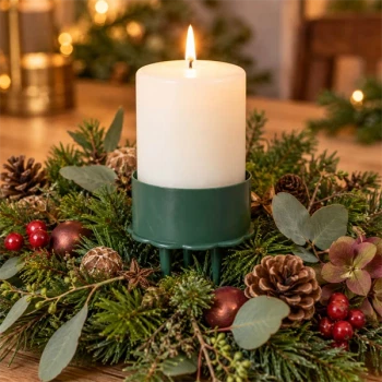 Grøn lysholder til bloklys i stemningsfuld juledekoration med gran og kogler