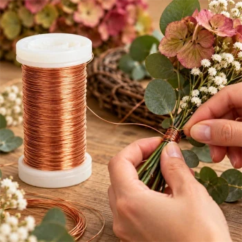 Hænder binder blomsterstilke og eucalyptus med kobberfarvet myrtetråd 0,5 mm fra en hvid spole.
