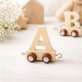 Navnetog bogstav A i naturtræ på lys træoverflade med bløde, nordiske børneværelsesdetaljer i baggrunden