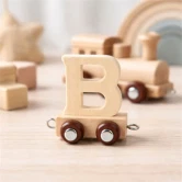 Navnetog bogstav B i naturtræ som togvogn på fødselsdagsbord med kage og lys i baggrunden