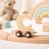 Navnetog bogstav C i naturtræ på træskinner i hyggeligt børneværelse med bamse og regnbue i baggrunden