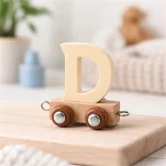 Navnetog bogstav D i naturtræ på togvogn placeret på træhylde i lyst børneværelse