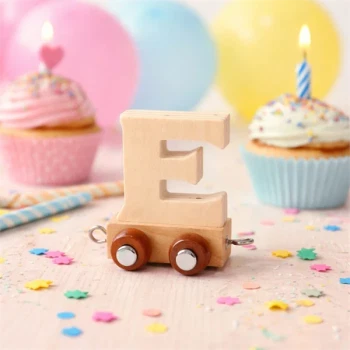Navnetog bogstav E i naturtræ på hjul omgivet af cupcakes, lys og konfetti til børnefødselsdag