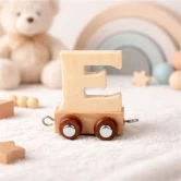 Navnetog bogstav E i naturtræ på hjul placeret på blødt underlag på børneværelse med bamse og regnbue i baggrunden