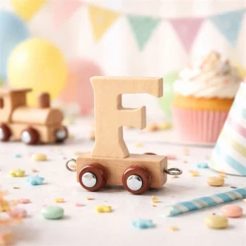 Navnetog bogstav F i naturtræ som trælegetøj på bord med farverig børnefødselsdag pynt, cupcake og balloner i baggrunden