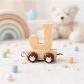 Navnetog bogstav J i naturtræ på togvogn omgivet af børnefødselsdagsdekorationer og pastelpynt