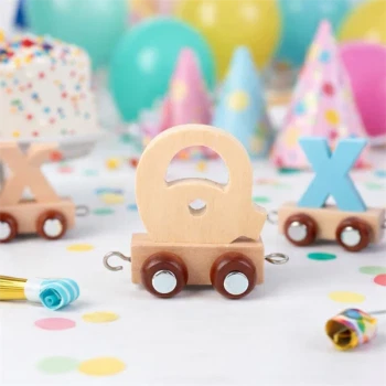 Navnetog bogstav Q i naturtræ som trælegetøj på bord til børnefødselsdag med balloner og festpynt