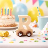 Navnetog bogstav R i naturtræ som dekoration til børnefødselsdag med farverig festpynt og kage i baggrunden