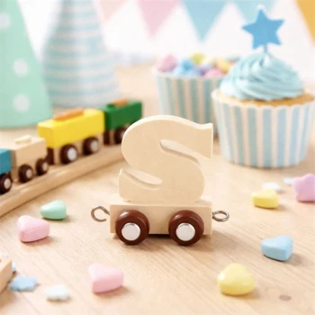 Navnetog bogstav S i naturtræ som trælegetøj på bord med cupcakes og pynt til børnefødselsdag