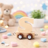 Navnetog bogstav S i naturtræ som trælegetøj på bord med bamse, regnbue og pastelfarvet pynt på børneværelse