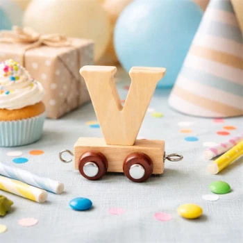 Træ navnetog bogstav V i naturtræ som dekoration til børnefødselsdag med farverigt pynt og legetøj