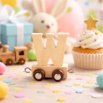 Navnetog bogstav W i naturtræ på togvogn pyntet til børnefødselsdag med konfetti og cupcake i baggrunden