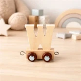 Navnetog bogstav W i naturtræ på togvogn placeret på bord i lyst børneværelse med nordisk indretning