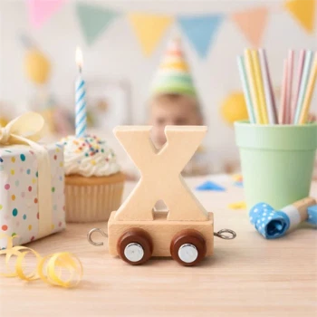 Navnetog bogstav X i naturtræ på bord til børnefødselsdag med cupcake, gave og farverig pynt i baggrunden