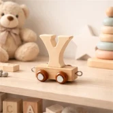 Navnetog bogstav Y i naturtræ på hylde i hyggeligt børneværelse med bamse og trælegetøj i baggrunden