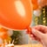 Close-up af orange ballon 30 cm hvor knuden bindes – latex ballon til fest og dekoration