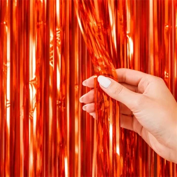 Close-up af orange glimmerforhæng med skinnende folie strimler holdt i hånden