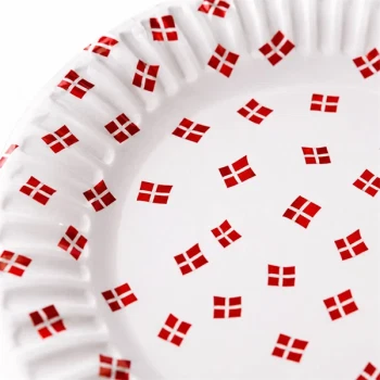 Close-up detaljebillede af paptallerken med små Dannebrog flag i rød og hvid på hvid baggrund