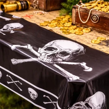 Close-up af pirat dug i plast med kranie og korslagte knogler på bord med skattekiste og guldmønter til pirat fødselsdag