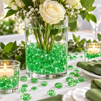 Grønne Raindrops som bordpynt i glasvase med hvide roser, grønne blade og levende lys – elegant blomsterdekoration til fest.