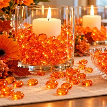 Raindrops Orange dekorationsdråber i glas med levende lys, orange blomster og efterårspynt på et festligt bord.
