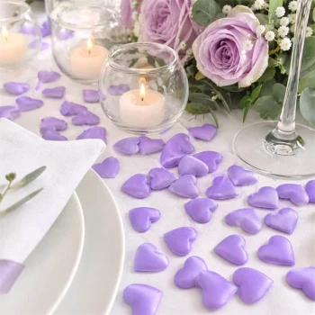 Smaa lilla stof hjerter som romantisk bordpynt til bryllup med stearinlys og blomsterdekoration