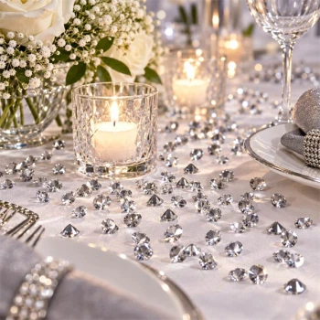 Sølv bordpynt med pynte diamanter, levende lys og hvide blomster på elegant festbord
