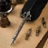 Close-up af sort fjerpen med dekorativt metalhåndtag og udskiftelige kalligrafi-spidser på vintage papir.