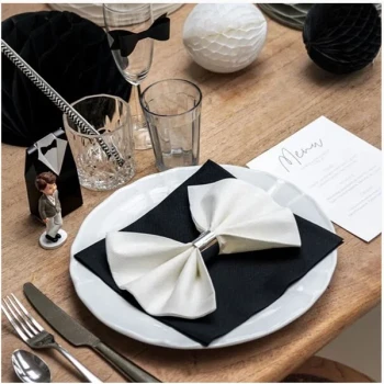 Sort og hvid serviet foldet som butterfly på hvid tallerken ved elegant festbord med glas, bestik og bordpynt