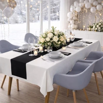 Elegant pyntet festbord dækket med hvid Sovie airlaid papirdug, sort bordløber, blomsterdekoration og levende lys