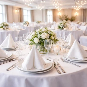 Elegant festbord dækket med hvide Sovie tissue servietter, foldede servietter på tallerkener, glas, bestik og blomsterdekoration